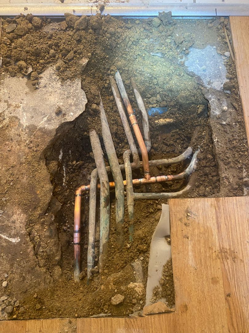Exposed pipework and replacement fittings beneath an opened floor
